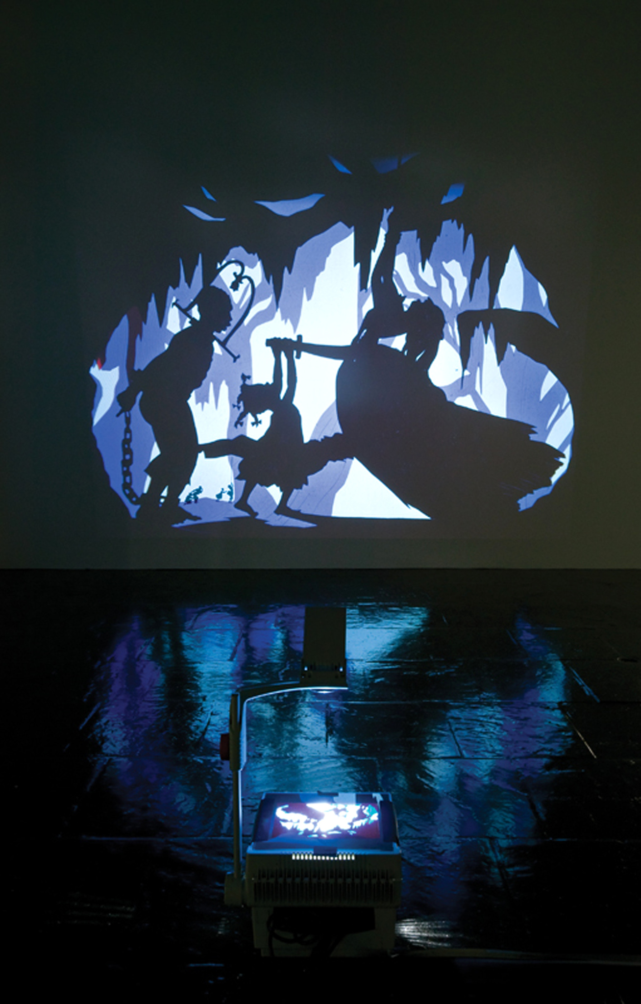Silhouetted figures projected on a wall above an overhead projector in a dark room.