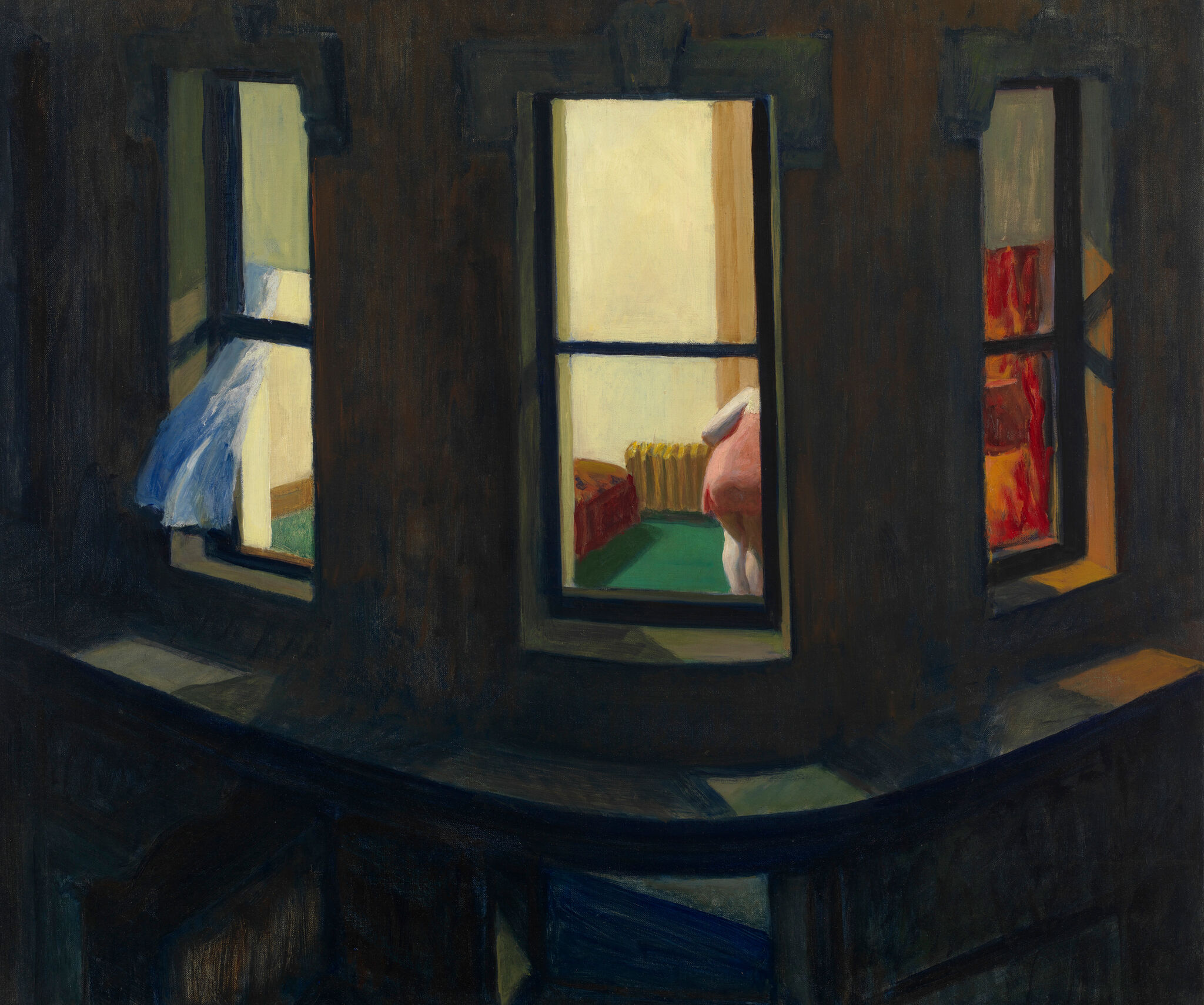 A woman in a window illuminated at night.